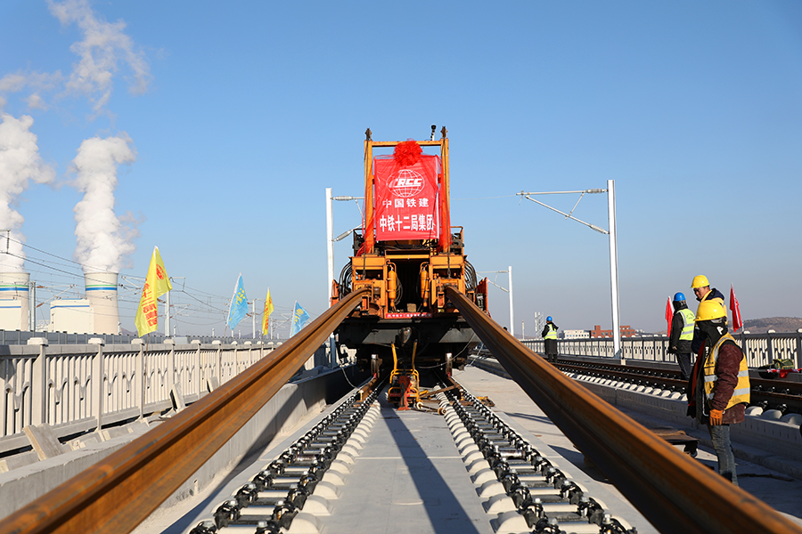 日前，朝凌高鐵無(wú)砟道床段落鋼軌全線鋪通。朝凌高鐵自京沈高鐵遼寧朝陽(yáng)站引出，經(jīng)遼寧朝陽(yáng)市、北票市、錦州市后接入京哈鐵路秦沈段（秦沈客專）的凌海南站，建設(shè)里程105公里，設(shè)計(jì)時(shí)速350公里，是我國(guó)東北地區(qū)高速鐵路網(wǎng)的重要組成部分。圖為中國(guó)鐵建所屬中鐵十二局建設(shè)者操作軌道牽引車(chē)進(jìn)行最后一組500米長(zhǎng)鋼軌鋪設(shè)。（李煜 攝）
