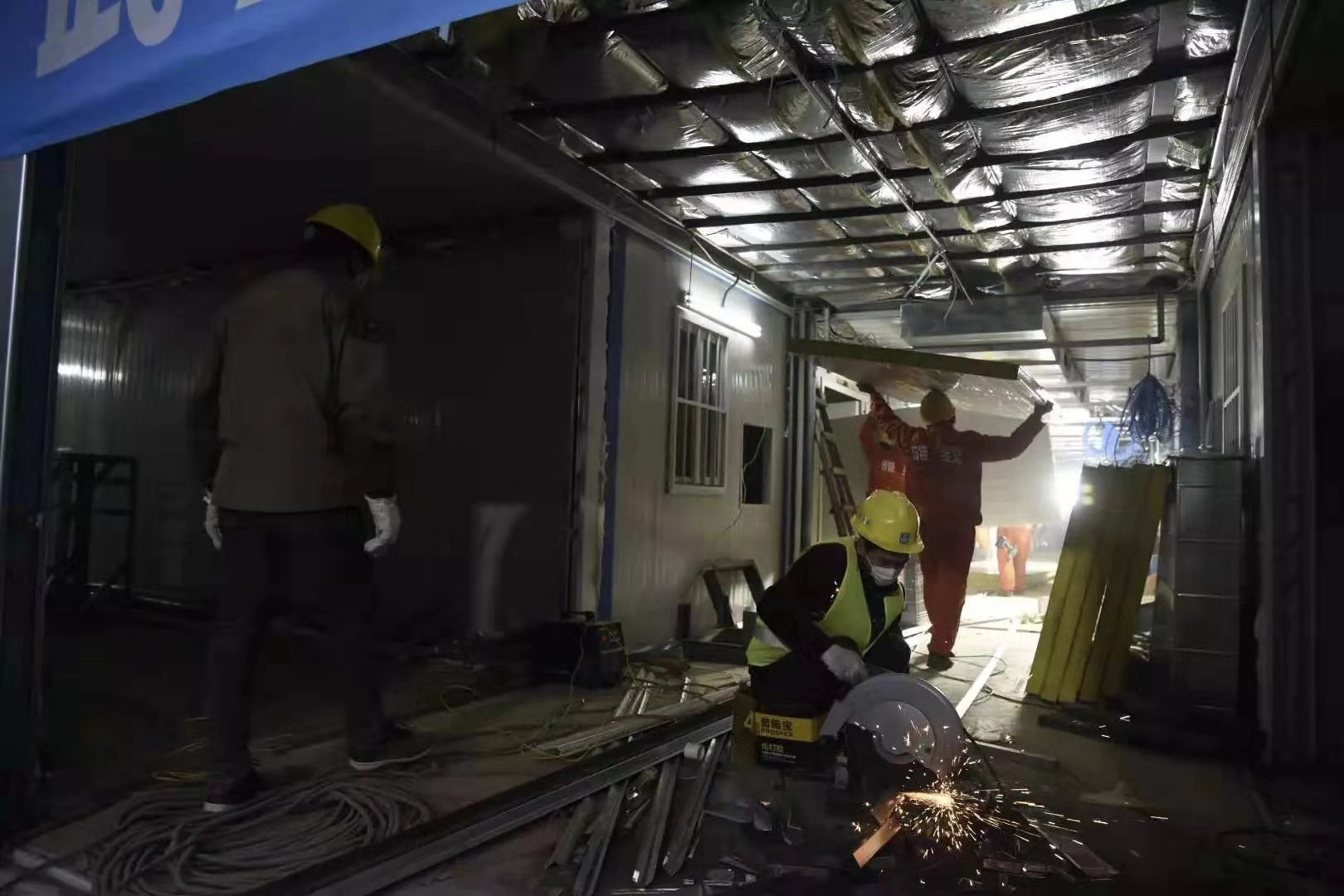 為了優(yōu)質(zhì)高效地推進(jìn)火神山醫(yī)院項目實施，1月25日項目啟動之時，中建三局現(xiàn)場成立了6支、322名員工組成的青年突擊隊，青年員工們紛紛請戰(zhàn)，并且從全國各地“逆行”馳援武漢參戰(zhàn)。為保證施工進(jìn)度，青年突擊隊制定了“小時制”作戰(zhàn)地圖，搭建了工程“大數(shù)據(jù)”，并采取24小時輪班作業(yè)，突擊隊員不畏疫情兇險，精誠團(tuán)結(jié)、通力合作，很多人不眠不休沖鋒在施工一線。圖為2月1日17時30分，火神山醫(yī)院一號樓，施工人員在進(jìn)行室內(nèi)裝潢。