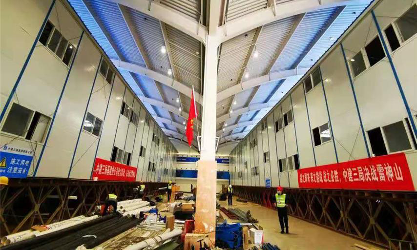 截至1月30日中午12時，雷神山醫院項目總體建設進度完成40％。隔離病房區場地平整、溝槽開挖、溝槽管線預埋、非溝槽區PE膜施工全部完成，溝槽回填已完成90％，條形基礎施工完成60％；集裝箱總計進場1518間，場外改裝完成約300套，現場已完成吊裝30間。醫護人員生活區A1－A7棟完成板房框架梁柱、樓面板、墻面板、屋面板等結構施工的70％。圖為醫護住宿區板房結構施工現場。