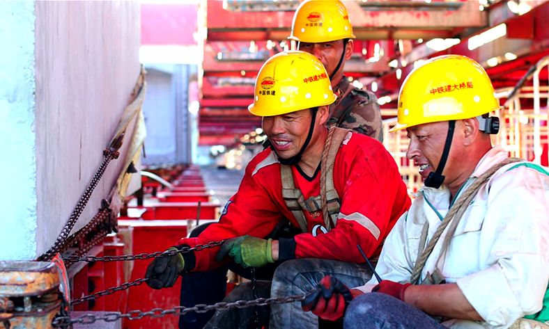 圖為工作人員調(diào)整最后一片鐵路節(jié)段梁。