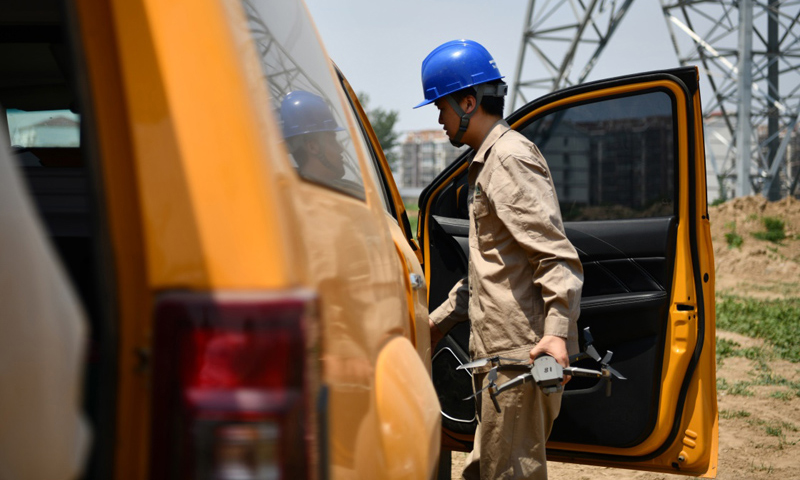 圖為6月24日，電力工人從車上取出無(wú)人機(jī)準(zhǔn)備開始巡檢工作。（新華社記者 李然 攝）