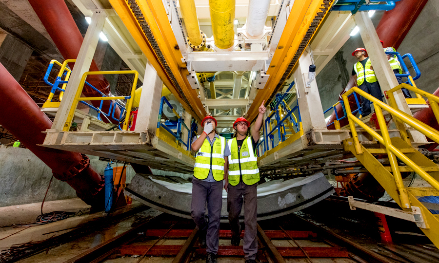近日，中國鐵建所屬中鐵二十二局軌道公司廣州地鐵18號和22號線項目通過加長洞門鋼環寬度，在鋼環內圈安裝盾尾密封刷進行注脂，實現了洞門雙重止水效果，有效克服了廣州市富水沙層盾構始發的技術難題。日前，該項目部首臺大直徑泥水盾構機始發。圖為技術人員在討論解決方案。（桂天奇 攝）