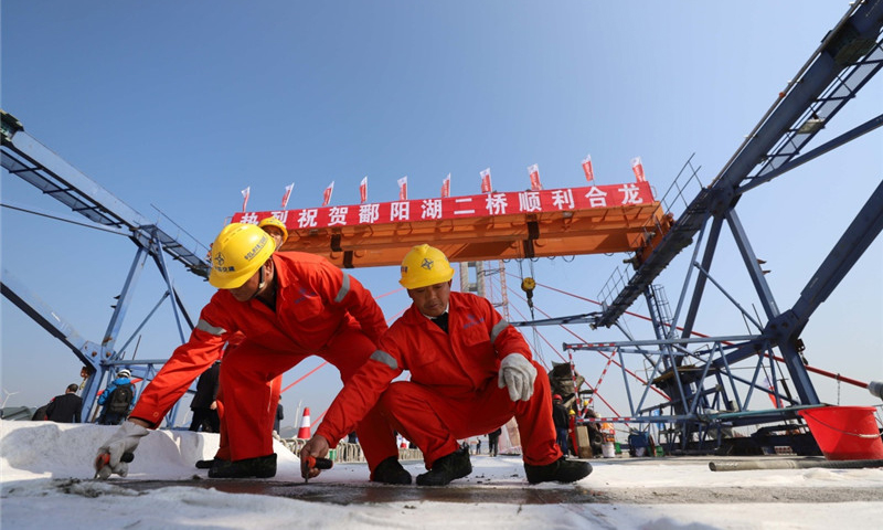 圖為11月28日，兩名工人在鄱陽湖二橋橋面上進行收面施工。新華社發（韓俊烜 攝）