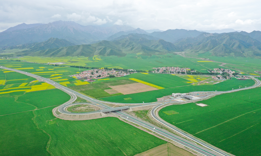 作為祁連山下的重要交通基礎(chǔ)設(shè)施工程，每年8月，張扁高速公路沿線的油菜花競(jìng)相盛開，怡人的景色還吸引著大量的游客自駕前往，營(yíng)造了“車在路上行，人在畫中游”的和諧美景。圖為祁連山與張扁高速公路。趙森 攝
