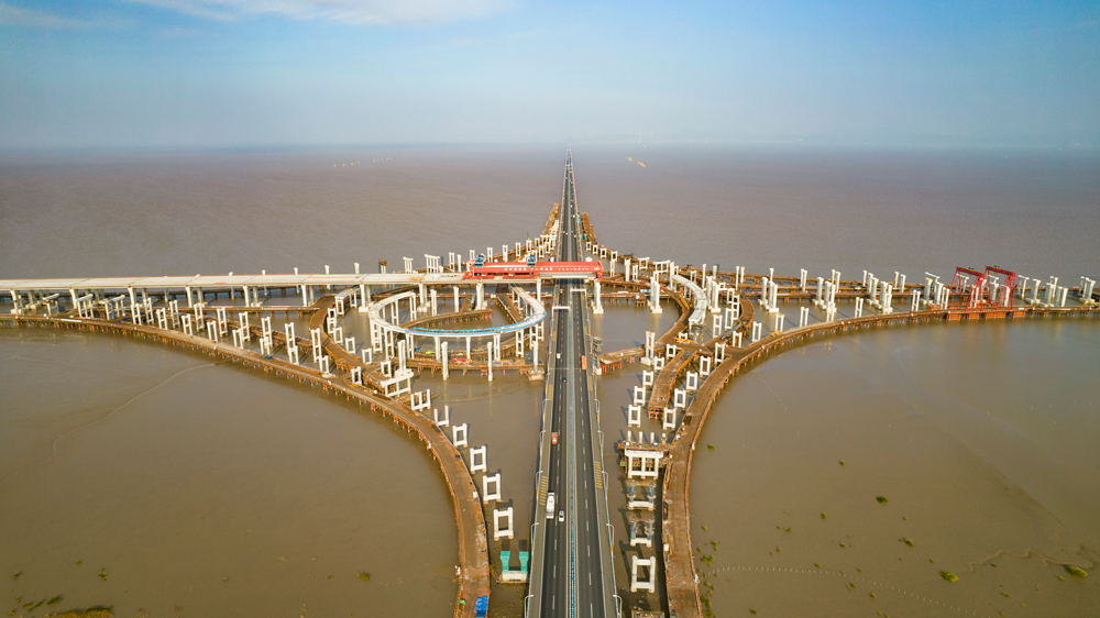 杭甬高速復線寧波一期工程全長55.833千米，為雙向六車道高速公路標準，設計時速120千米。該工程主線橋在寧波市鎮海區一跨直接越過甬舟高速金塘大橋，并設濱海互通與金塘大橋相接，主線橋箱梁梁底與金塘大橋橋面凈空約7.6米，海上架梁施工安全風險極高，為全線唯一一處Ⅳ級施工風險點。圖為濱?；ネㄖ骶€橋跨越金塘大橋架梁現場。