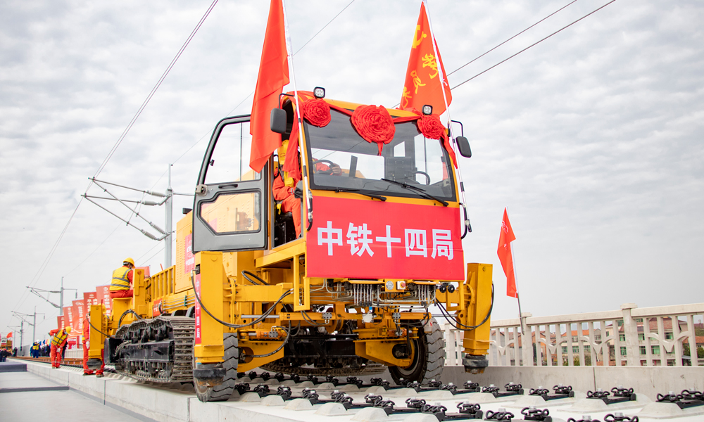 項目部克服異形梁、橋機頻繁調頭、高溫暴雨、小曲線、大坡度等不利因素和架梁難題，先后使用下導梁羅盤調平技術、龍門吊安裝走行糾偏裝置、運梁車安裝防疲勞人臉識別系統等先進技術和設備，將信息化運用到視頻監控、風速監測、胎壓監測、鋼絲繩監測等各個方面，為箱梁架設做好技術和安全保障。圖為多功能鋪軌機。