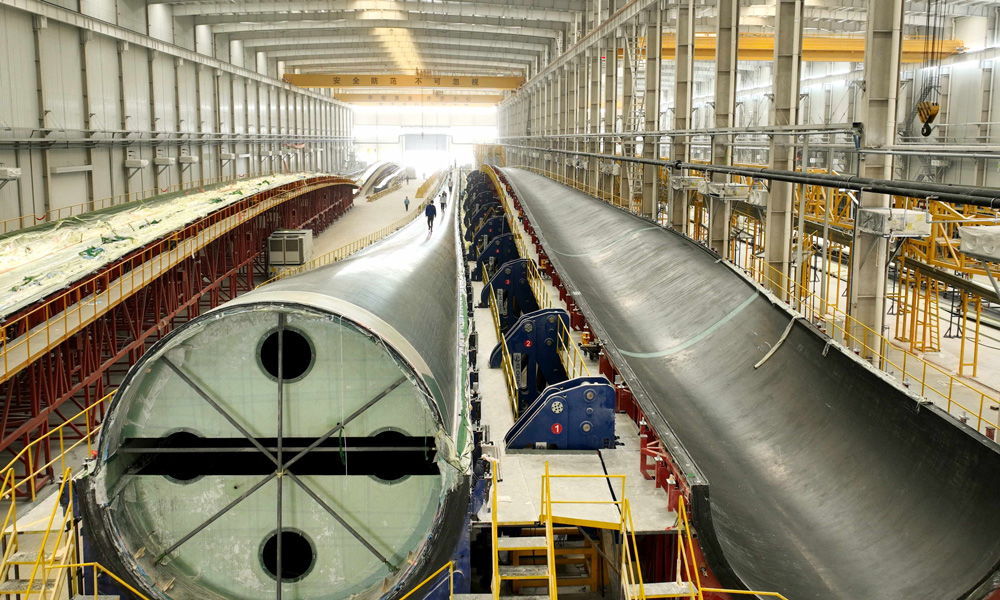 東方風電B1200A、B1260A是配套I-II類風區13-18MW海上風電機組的超長葉片，是企業打造的兩款高效低載輕量化葉片。這兩款葉片采用東方風電自主研發的大厚度、鈍尾緣、高性能翼型，運用氣動結構一體化優化設計技術和彎扭耦合自適應降載技術，有效提高葉片的氣動性能并降低機組載荷；使用新材料，創新主梁結構，并基于部件級測試進行充分測試驗證，有效降低葉片重量和成本，確保葉片可靠性；攻克了新型主梁成型及超大超長葉片真空灌注、腹板一體式定位粘接等諸多工藝技術難題，保證產品的制造質量。圖為東方電氣質檢人員對B1260A型葉片進行外觀檢查。