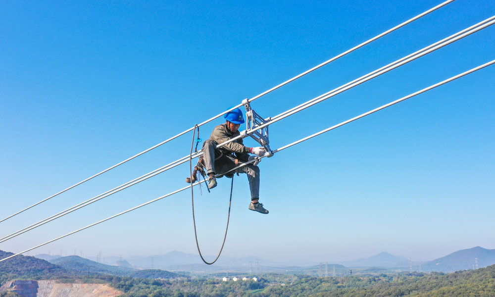 國家電網江蘇省送變電有限公司輸電人員在高空走線驗收消缺。