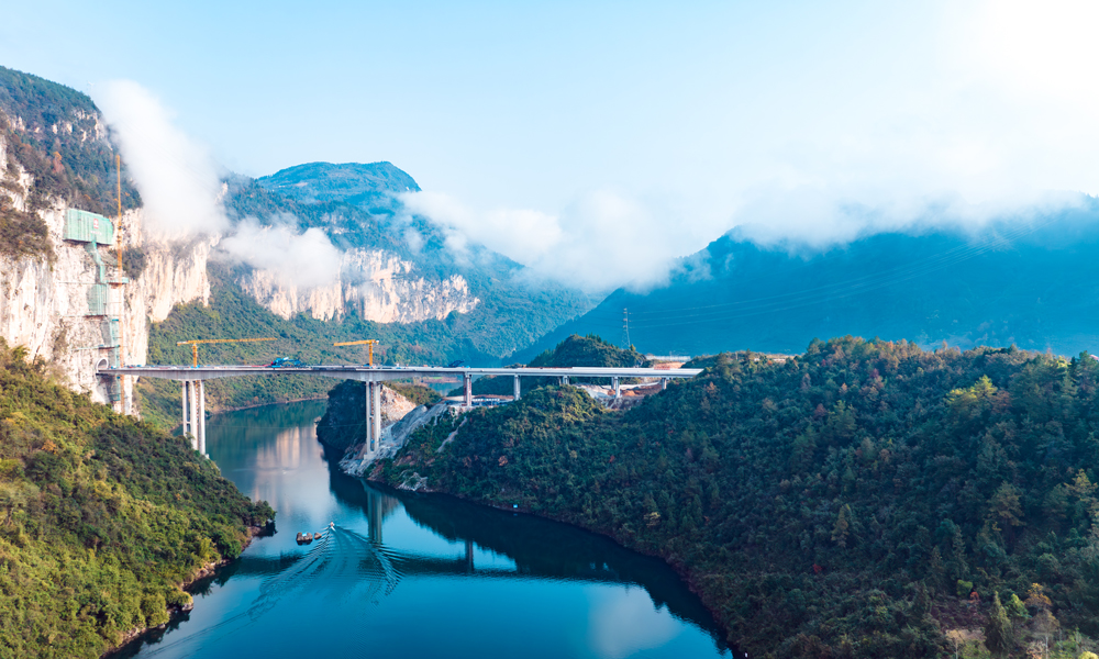 渝湘復(fù)線高速公路總里程280公里，由巴南至彭水、彭水至酉陽(yáng)、武隆至道真3條路組成，平均橋隧比80%。圖為阿蓬江大橋施工現(xiàn)場(chǎng)航拍側(cè)景。