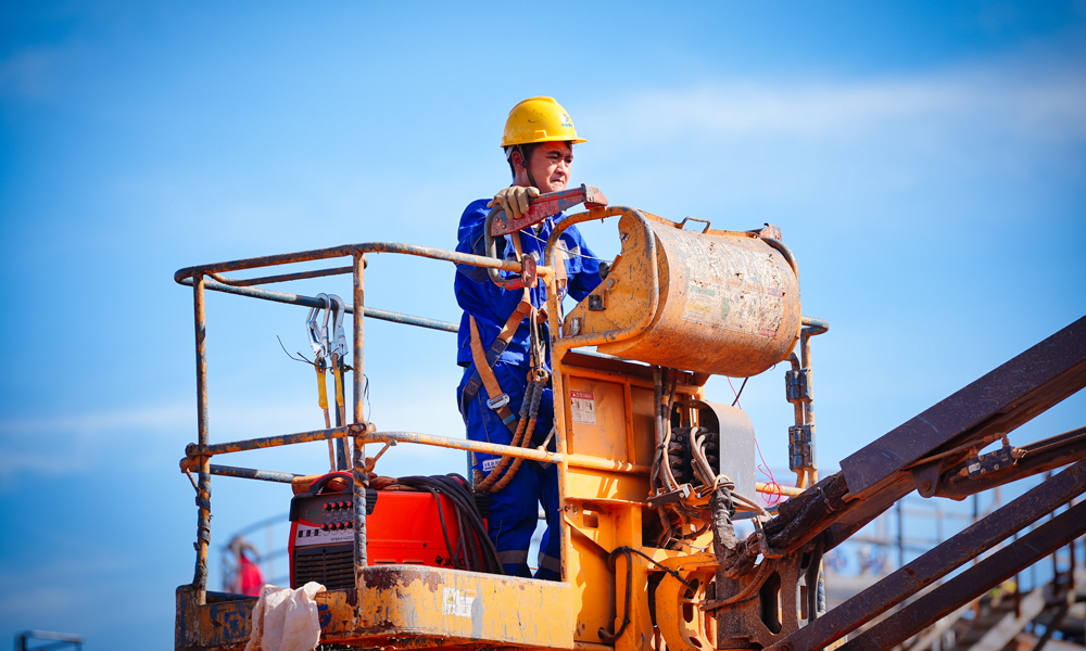 在陸地，建設人員倒排工期快施工，實現(xiàn)了原油處理站、生產(chǎn)水處理站、天然氣液化站、石油氣液化站、變電站、5G基站“六站合一”。其中，生產(chǎn)水處理站采用四級工藝處理生產(chǎn)水，處理后純凈度高。變電站將綠色岸電變壓后輸至海上平臺，替代傳統(tǒng)的燃氣發(fā)電，減碳效果突出。5G網(wǎng)絡“連通”海上，為無人機巡檢海上設施、海面24小時溢油苗頭監(jiān)測等各種智能應用鋪筑了“信息傳輸高速路”。圖為施工人員準備登高作業(yè)。