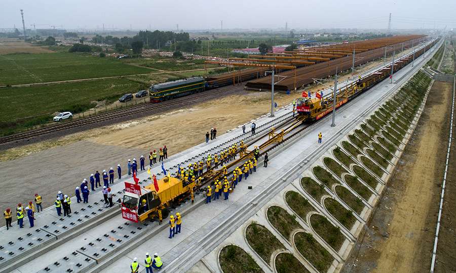 6月12日，在江蘇省東臺(tái)市的鹽通高鐵東臺(tái)站外施工現(xiàn)場(chǎng)，中國(guó)鐵建所屬中鐵十一局鋪軌機(jī)牽引著第一組500米長(zhǎng)鋼軌平穩(wěn)地落在無(wú)砟道床上，標(biāo)志著我國(guó)“八縱八橫”高鐵網(wǎng)沿海通道重要組成部分的鹽通高鐵建設(shè)整體從線(xiàn)下施工轉(zhuǎn)入線(xiàn)上軌道鋪設(shè)階段。圖為鹽通高鐵全線(xiàn)首鋪現(xiàn)場(chǎng)。（劉連強(qiáng) 攝）